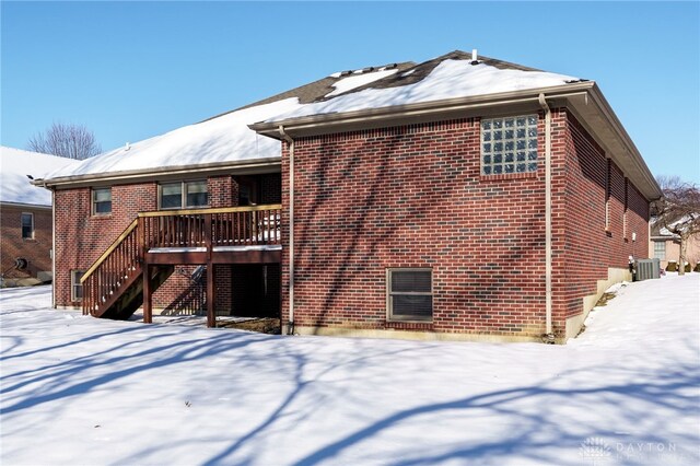 snow covered back of property featuring central air condition unit