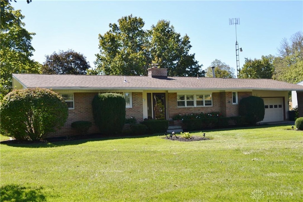 single story home with a garage, brick siding, a front lawn, and a chimney