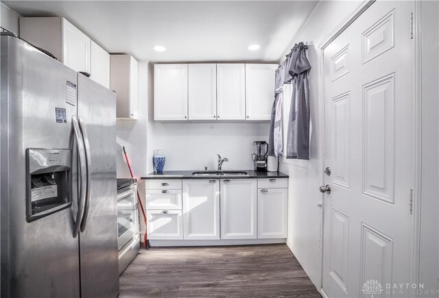 kitchen with appliances with stainless steel finishes, sink, dark hardwood / wood-style flooring, and white cabinetry