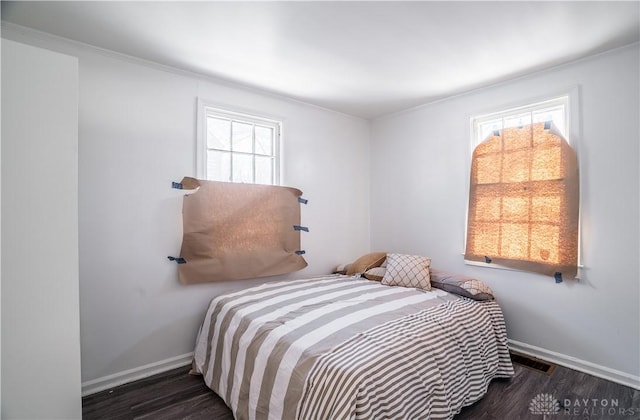 bedroom with dark hardwood / wood-style floors and multiple windows