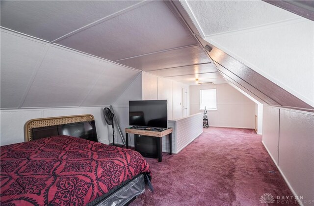 bedroom featuring carpet, vaulted ceiling, and a textured ceiling