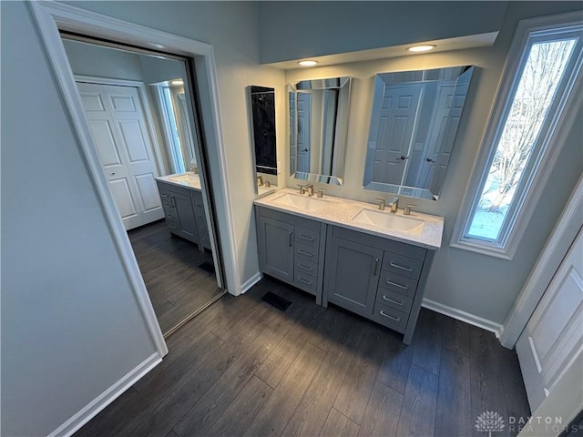 bathroom with double vanity, a wealth of natural light, a sink, wood finished floors, and baseboards