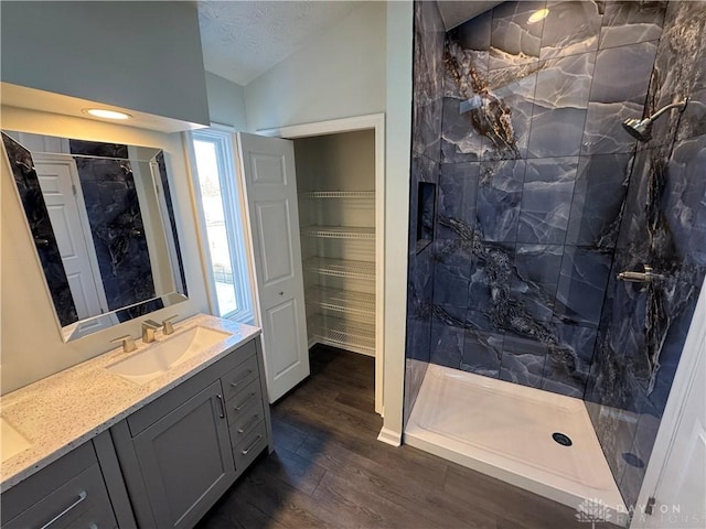 bathroom featuring wood finished floors, vanity, vaulted ceiling, a closet, and a marble finish shower