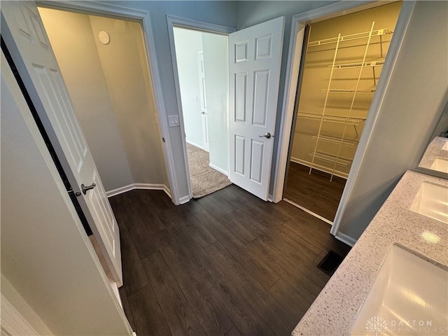 hallway featuring a sink, baseboards, and dark wood-type flooring