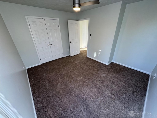 unfurnished bedroom with a ceiling fan, dark colored carpet, a closet, and baseboards