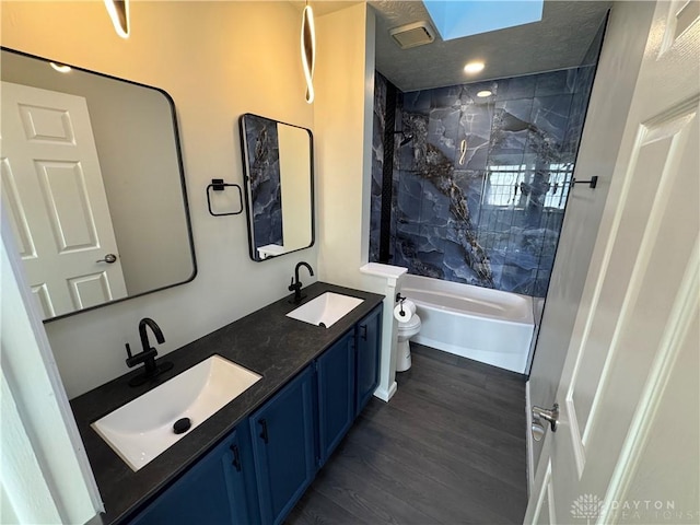 full bathroom with a sink, bathing tub / shower combination, toilet, and wood finished floors