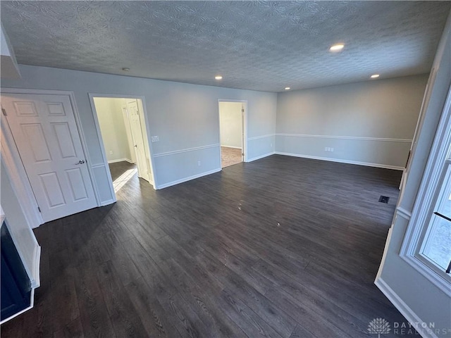 unfurnished room featuring a textured ceiling, recessed lighting, dark wood finished floors, and baseboards