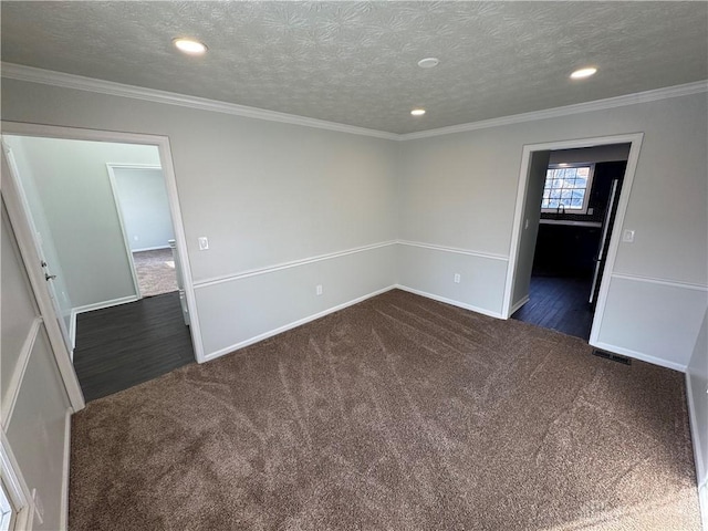 empty room featuring visible vents, ornamental molding, dark colored carpet, a textured ceiling, and recessed lighting