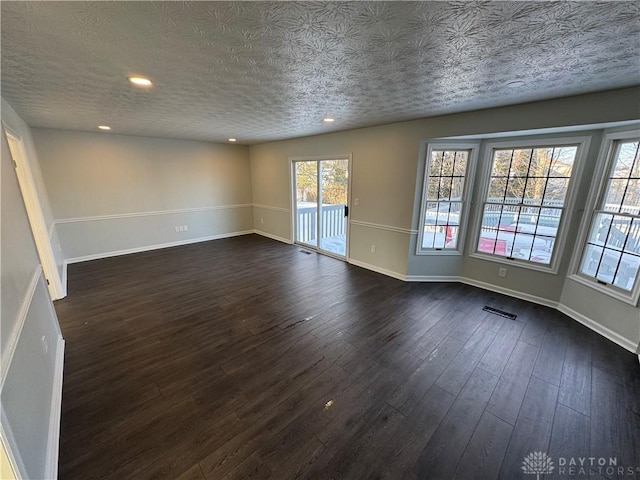 unfurnished room featuring dark wood-type flooring, recessed lighting, visible vents, and baseboards