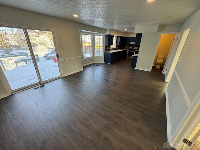 kitchen featuring a textured ceiling, electric range, dark wood-type flooring, visible vents, and light countertops