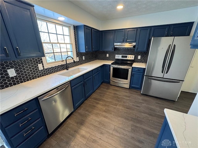 kitchen with blue cabinets, under cabinet range hood, appliances with stainless steel finishes, and a sink