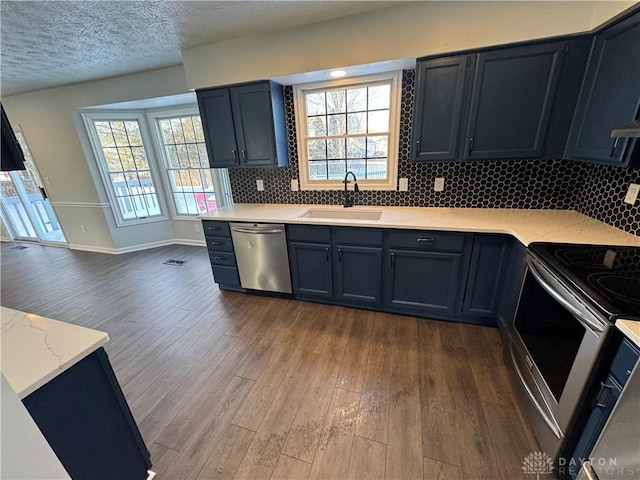 kitchen featuring dark wood-style flooring, stainless steel appliances, tasteful backsplash, a sink, and a textured ceiling