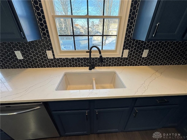 kitchen featuring stainless steel dishwasher, a sink, light stone countertops, and decorative backsplash