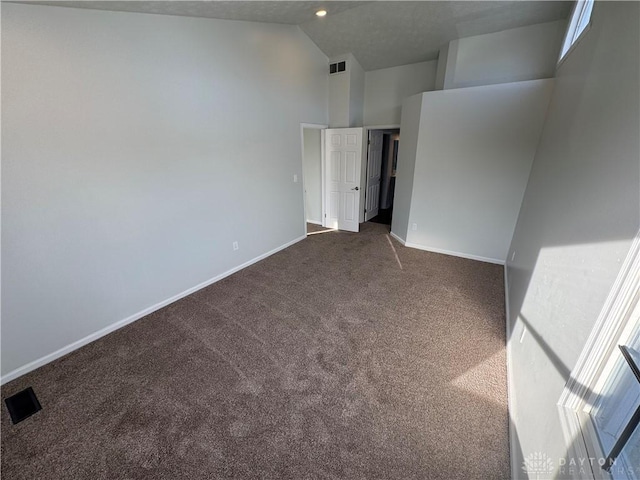 unfurnished room featuring dark colored carpet, high vaulted ceiling, visible vents, and baseboards