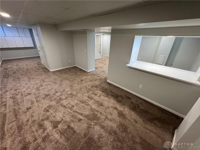 finished below grade area featuring carpet, baseboards, and a drop ceiling