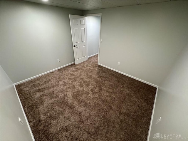 empty room with a paneled ceiling, carpet, and baseboards