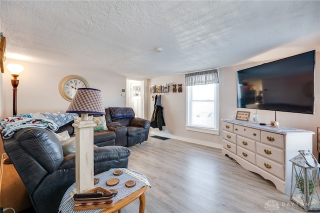 living room with a textured ceiling and light wood-type flooring