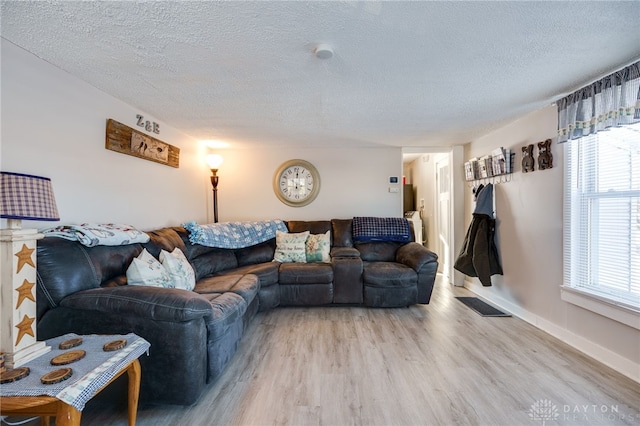 living room with a textured ceiling and light wood-type flooring