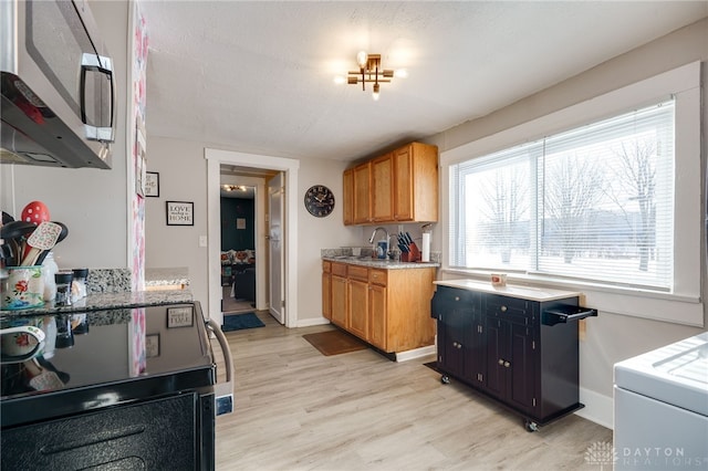 kitchen featuring sink, a textured ceiling, light hardwood / wood-style floors, and electric stove