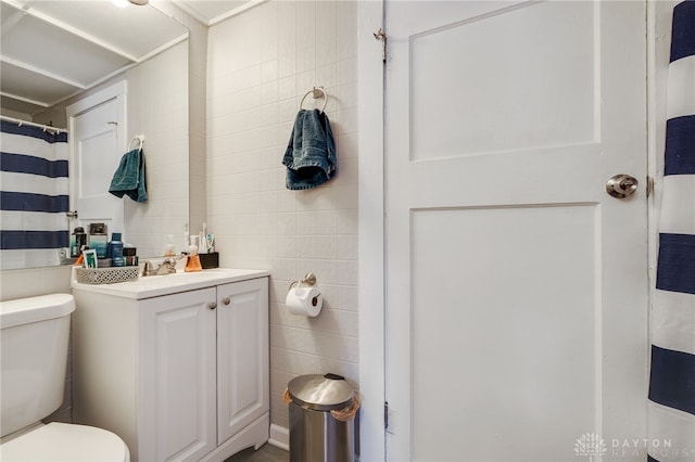 bathroom featuring tile walls, vanity, and toilet