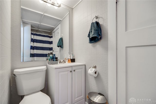 bathroom featuring vanity, tile walls, and toilet