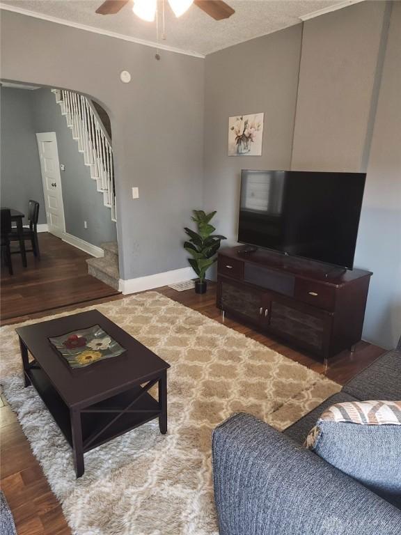 living room with a textured ceiling, ceiling fan, ornamental molding, and hardwood / wood-style floors