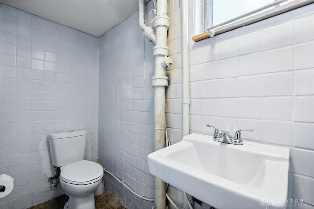 bathroom with toilet, tile walls, and sink