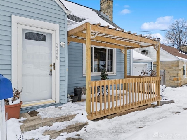 snow covered property entrance with a pergola