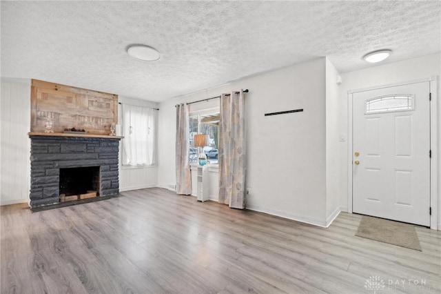 foyer with a textured ceiling, light wood-type flooring, and a fireplace