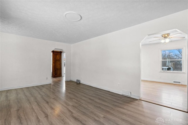 unfurnished room with ceiling fan, a textured ceiling, and dark hardwood / wood-style floors