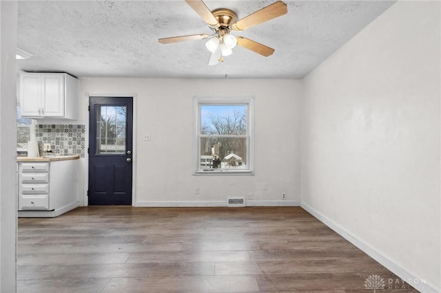 interior space with ceiling fan, a textured ceiling, and hardwood / wood-style floors