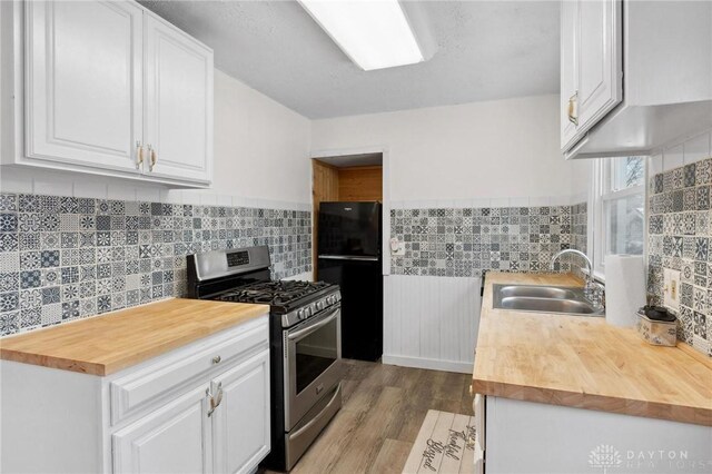 kitchen featuring sink, white cabinets, and stainless steel gas range oven