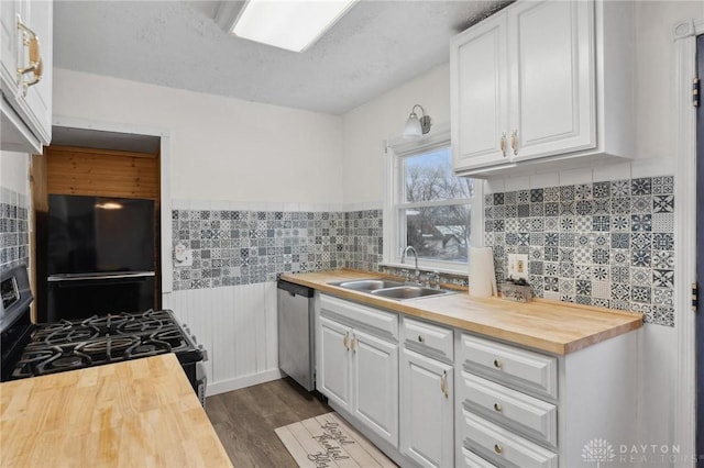 kitchen with black appliances, sink, wood counters, and white cabinetry