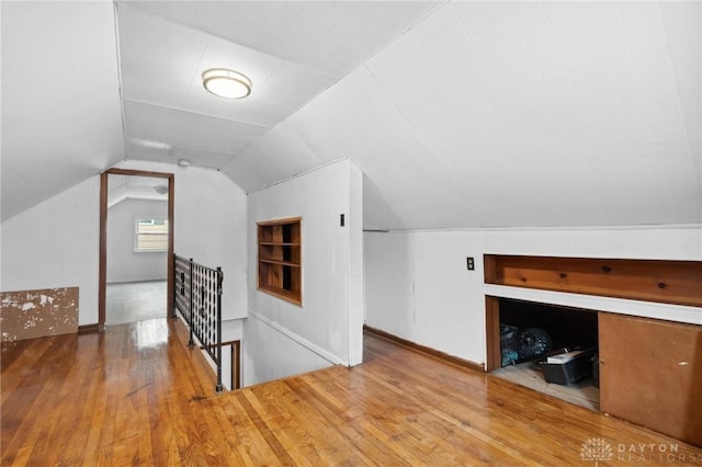 bonus room featuring lofted ceiling, hardwood / wood-style floors, and built in shelves