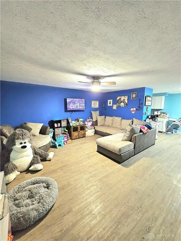 living room featuring hardwood / wood-style flooring, a textured ceiling, and ceiling fan