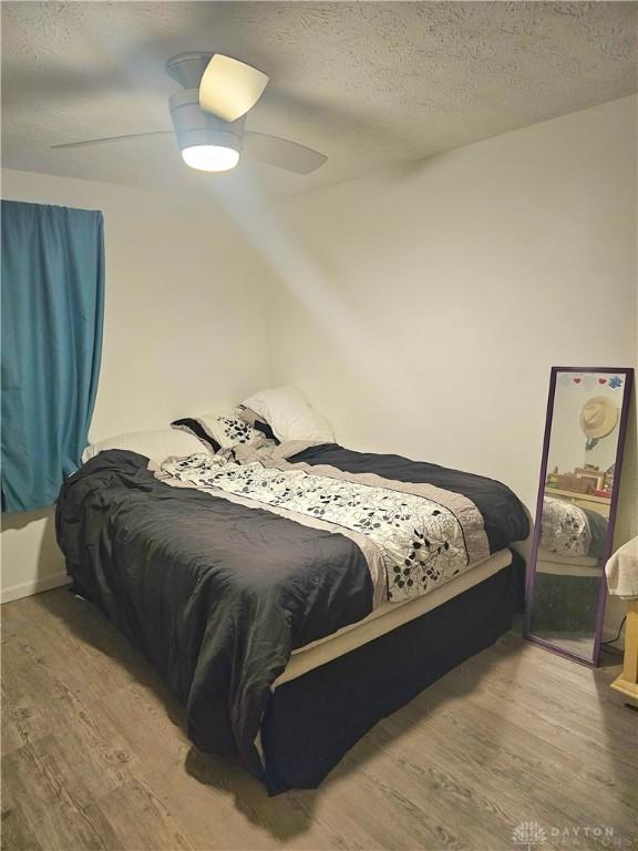 bedroom with ceiling fan, a textured ceiling, and hardwood / wood-style flooring