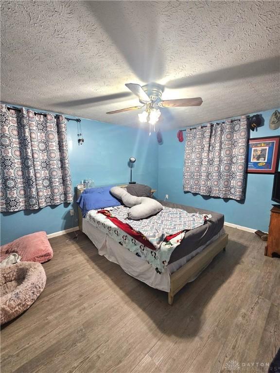 bedroom with ceiling fan, a textured ceiling, and hardwood / wood-style flooring