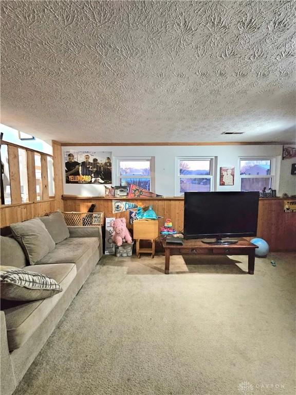 carpeted living room with a textured ceiling and ornamental molding