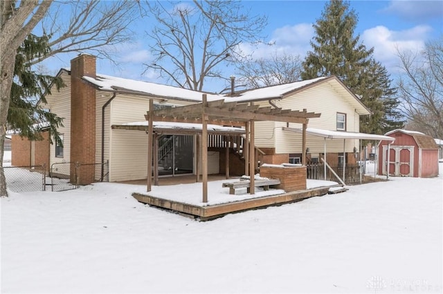 snow covered back of property featuring a deck and a shed