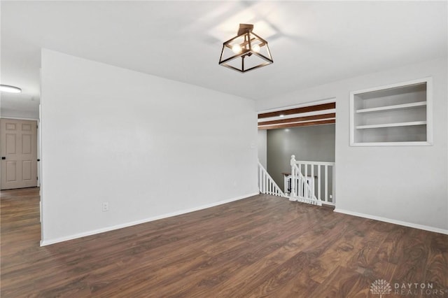 unfurnished room with beam ceiling, dark hardwood / wood-style floors, and built in shelves