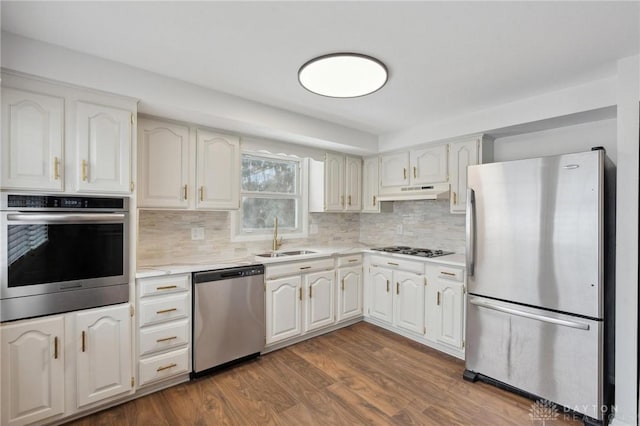 kitchen with stainless steel appliances, backsplash, white cabinets, and sink