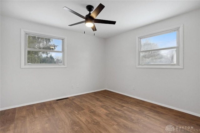 spare room featuring ceiling fan, dark hardwood / wood-style flooring, and a healthy amount of sunlight