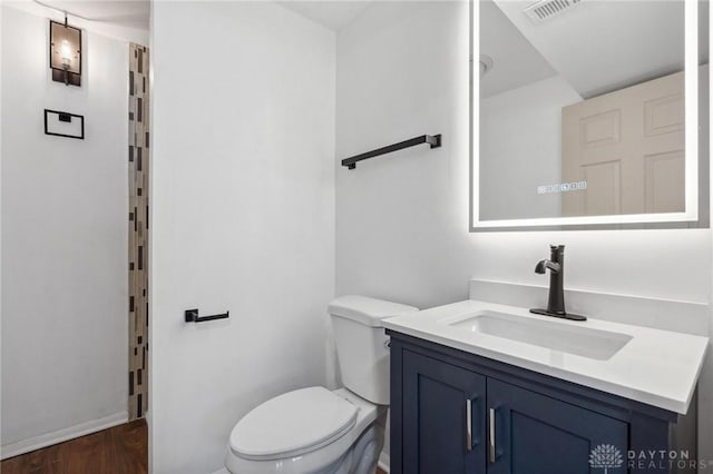 bathroom with toilet, hardwood / wood-style floors, and vanity