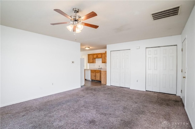 unfurnished living room featuring ceiling fan, sink, and dark carpet