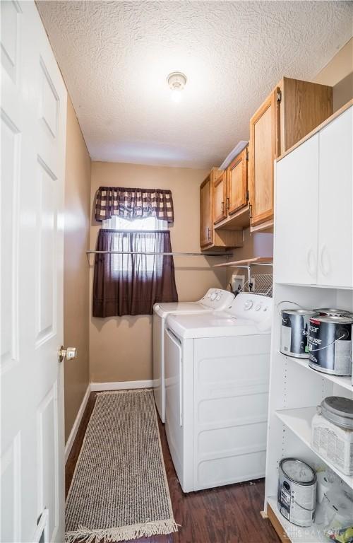 laundry area featuring a textured ceiling, cabinets, washer and dryer, and dark wood-type flooring