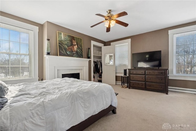 carpeted bedroom with ceiling fan, a closet, multiple windows, and a baseboard radiator