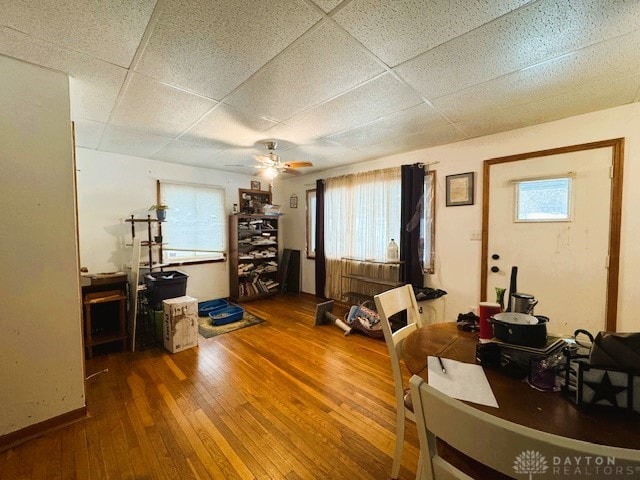 office space with ceiling fan, a paneled ceiling, plenty of natural light, and wood-type flooring