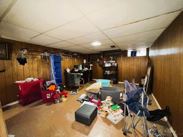 basement with a drop ceiling and wood walls