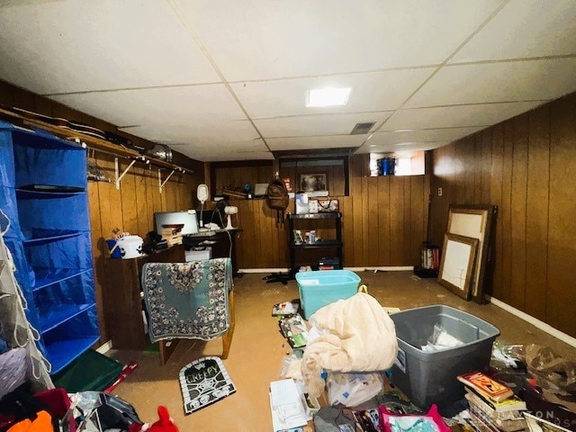 basement with a paneled ceiling and wood walls