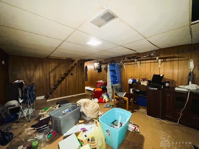 basement with a paneled ceiling and wood walls